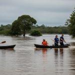 Flooded campsite in Brazil with rising water near tents and misty forest background.
